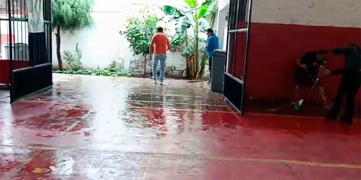 Padres de familia limpian cancha afectada por lluvias en Texmelucan; piden rehabilitación